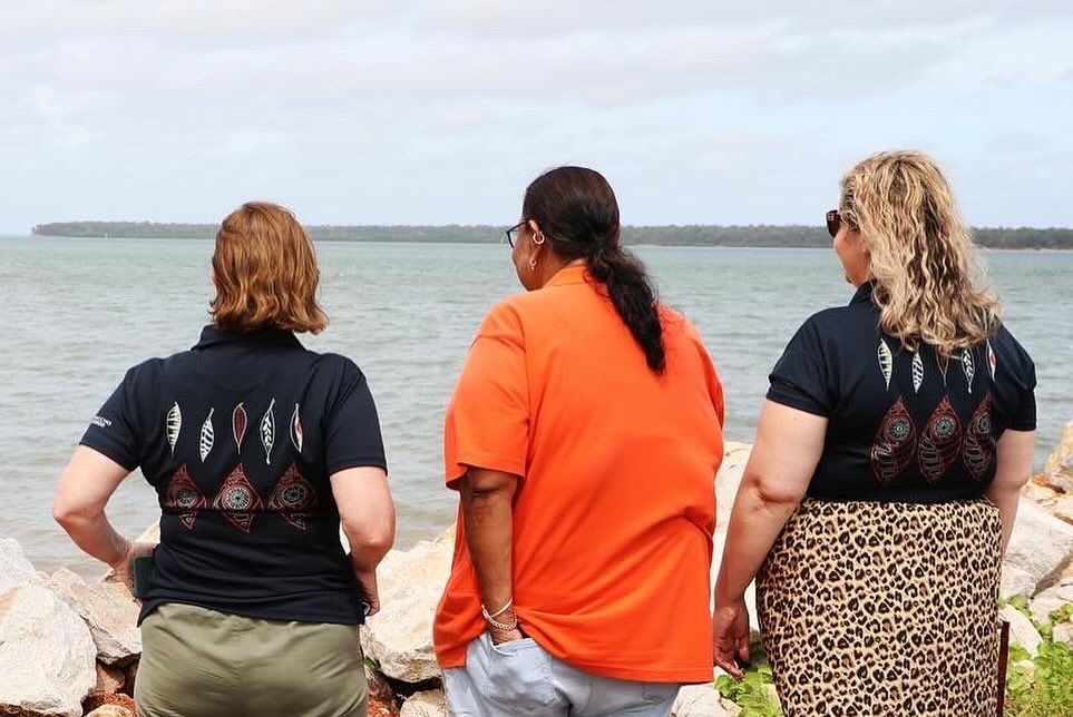 Three women standing together at the water's edge